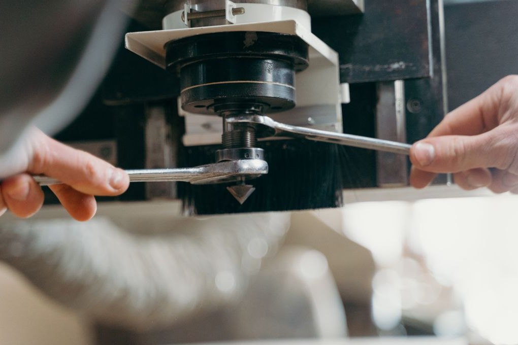 Hands using a wrench on industrial equipment
